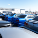 three r34-generation nissan skylines seen from the rear, parked in a densely packed outdoor storage lot in japan